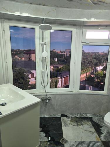 a bathroom with a shower and a sink and two windows at Bilgah Garden Villa in Bilgah