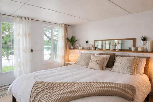 a white bedroom with a large bed with pillows at Chalet Cozy Spa sur Lac in Saint-André-Avellin