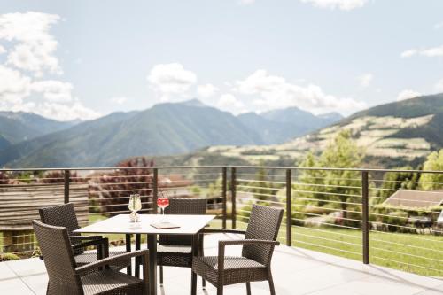 a table and chairs on a balcony with a view of mountains at Hotel Nussbaumerhof *** in Rodengo