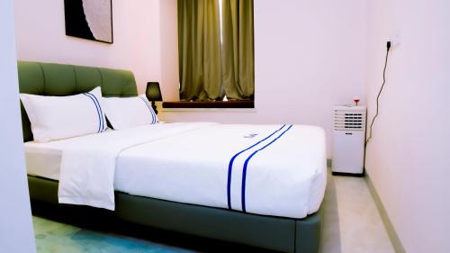 a bedroom with a white bed with a green headboard at Greenland HomeINN in Kigali