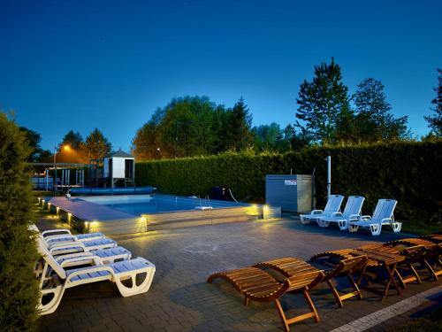 a group of lounge chairs and a swimming pool at Willa Alexandria - Basen, Cisza, Komfort - Domki i Apartamenty Karwia in Karwia