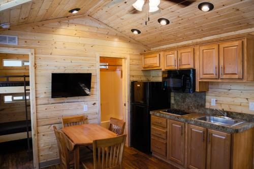 a kitchen with wooden cabinets and a wooden table with chairs at Ponderosa Camping Resort One-Bedroom Cabin 4 in Lotus
