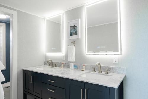 a bathroom with a sink and two mirrors at Waves Oceanfront Resort in Old Orchard Beach
