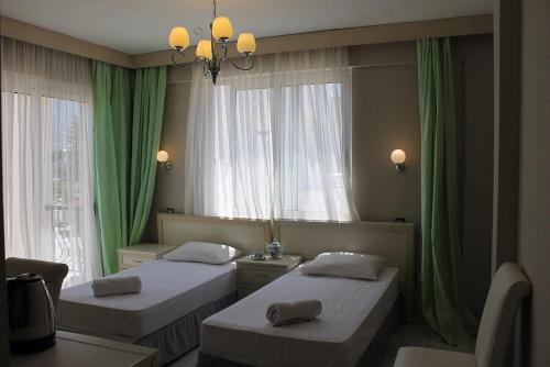 zwei Betten in einem Zimmer mit grünen Vorhängen in der Unterkunft Marsin Hotel & Bungalows in Kyrenia