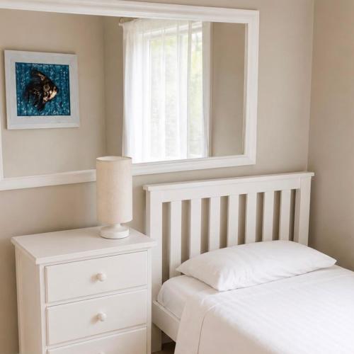 a white bedroom with a bed and a window at Diaz De Valle 35 in Mossel Bay