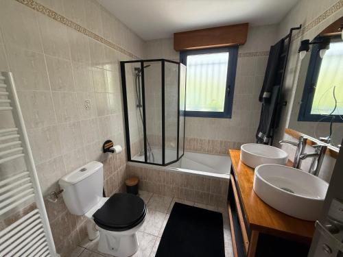 a bathroom with two sinks and a toilet and a shower at Suite à 800m de la plage in Saint-Lunaire