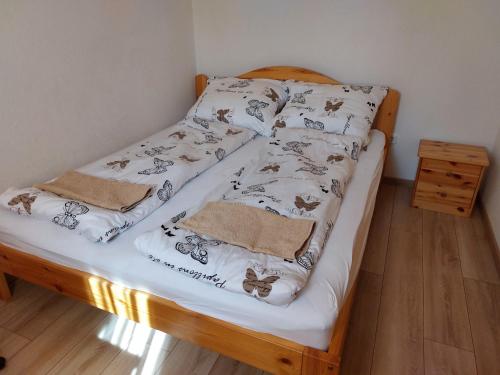 a twin bed with white sheets with butterflies on it at Azúr Vendégház in Hajdúszoboszló
