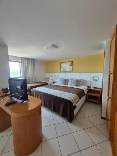 a hotel room with a bed and a desk with a computer at NATAL PLAZA PONTA NEGRA in Natal