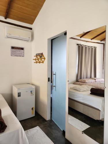 a room with two beds and a door to a bedroom at Pousada Aldeia Do Mar - Caraíva BA in Caraíva