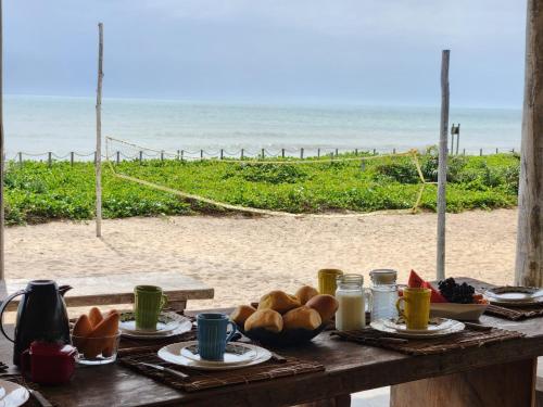 a table with bread and a view of the beach at Pousada Aldeia Do Mar - Caraíva BA in Caraíva