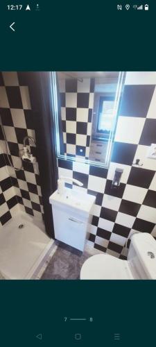 a bathroom with a black and white checkered wall at Powrót do Natury in Orzyny