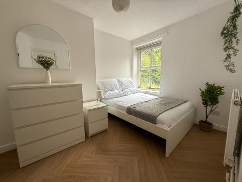 a white bedroom with a bed and a window at Spacious Central Flat with Parking in Bangor