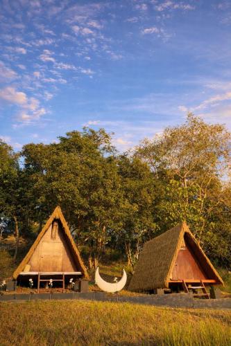 two thatched buildings in a field with trees at Abot Langit Calatagan in Calatagan