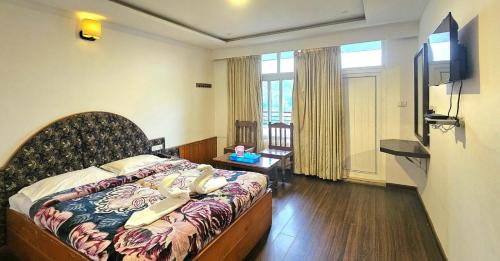 a hotel room with a bed and a television at hotel ruby international in Kodaikānāl