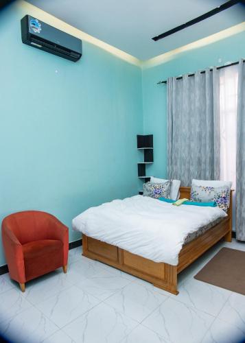 a bedroom with a bed and a red chair at RJ's Apartments Korogwe in Korogwe
