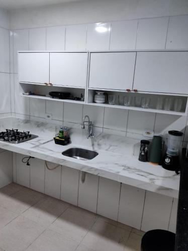 a white kitchen with a sink and a stove at Casa de praia in Marechal Deodoro