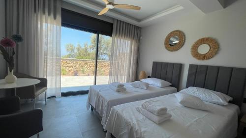 a bedroom with two beds and a table and a window at Carmelia Villas in Agios Nikitas