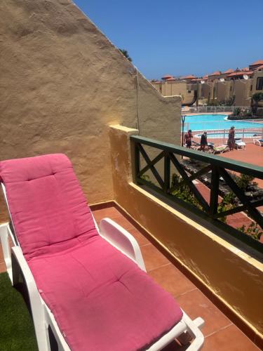 a pair of chaise lounge chairs on a balcony with a pool at Mi Amor in Caleta De Fuste