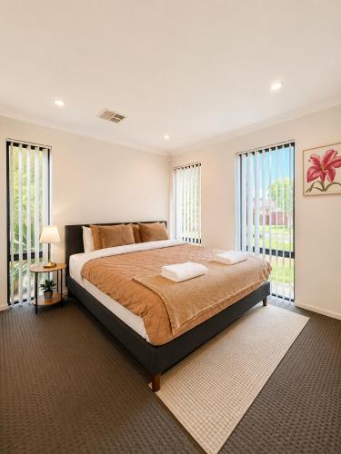 a bedroom with a large bed and windows at Modern oasis in Perth