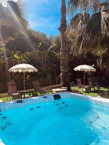 a swimming pool with two umbrellas and chairs at Villa Tiche in Cefalù
