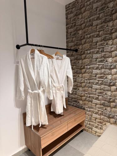 a rack of white shirts hanging on a brick wall at Theros Luxury Apartment in Archangelos
