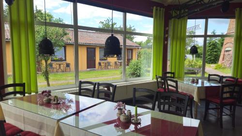 a dining room with tables and chairs and large windows at Holländer Mühle Rheinsberg in Rheinsberg