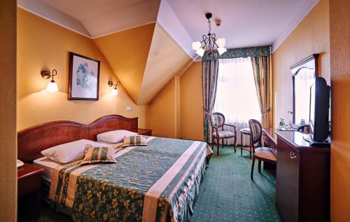 une chambre d'hôtel avec un lit, une table et des chaises dans l'établissement Villa Royal, à Ostrów Wielkopolski