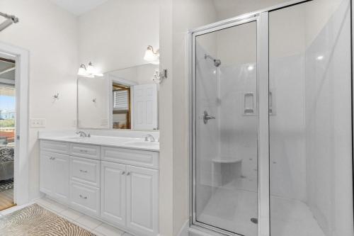 a white bathroom with a shower and a sink at Elegant Beachfront Escape with Wrap-Around Porches in Pawleys Island