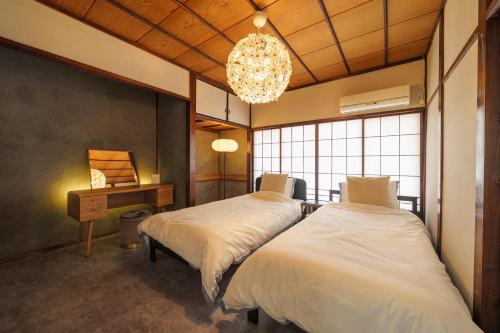 a bedroom with two beds and a desk and a chandelier at Tiger House Kusabana in Akiruno