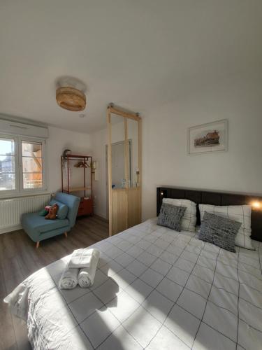 a bedroom with a large bed and a blue chair at Les couleurs de Schiltigheim - Aux portes de Strasbourg - Parlement in Schiltigheim