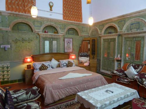 a bedroom with a large bed in a room with chairs at Tanisha Heritage Haweli in Bikaner