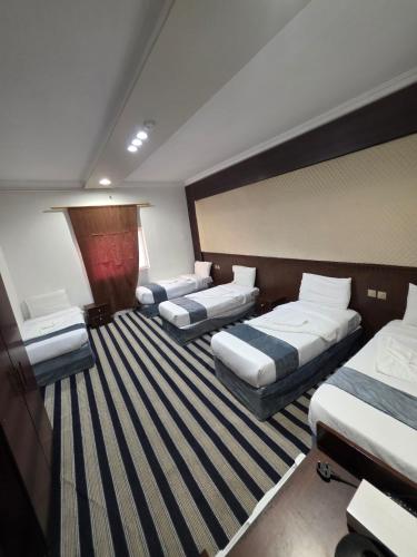 three beds in a hotel room with striped carpet at فندق مواسم الخير in Al ‘Azīzīyah