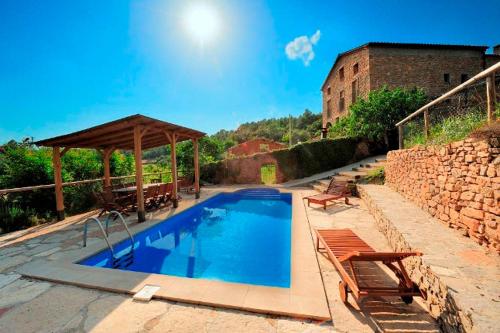 einen Pool mit Pavillon und Stühlen neben einem Gebäude in der Unterkunft Cal Solsona in La Baronia de Rialb