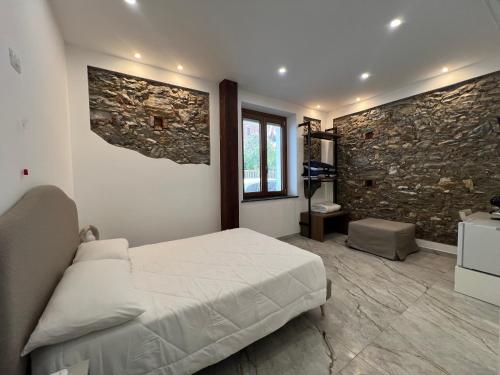 a bedroom with a bed and a stone wall at Kalispera Rooms in Scalea