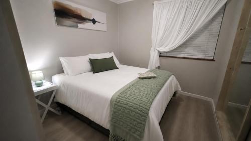 a small bedroom with a bed and a window at 6 Vasco Mews in Mossel Bay