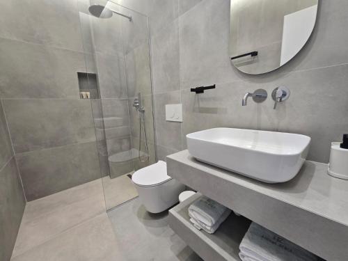 a bathroom with a sink and a toilet and a mirror at Rei Hotel in Borsh