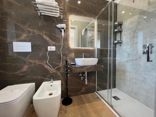 a bathroom with a toilet and a sink and a shower at Kalispera Rooms in Scalea