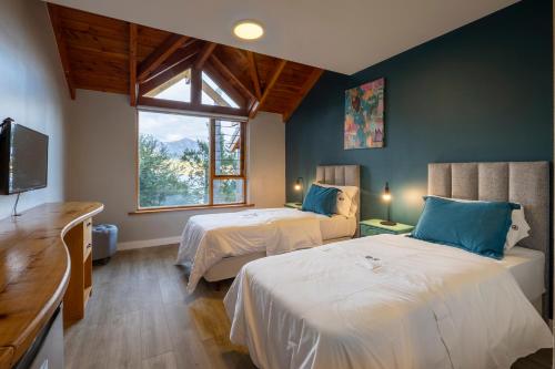 ein Schlafzimmer mit zwei Betten, einem Fernseher und einem Fenster in der Unterkunft Peninsula Petit in San Carlos de Bariloche