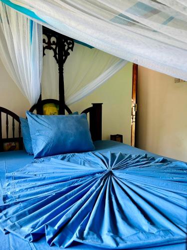 a blue comforter on a bed with a canopy at Embe Lodge in Kizimkazi