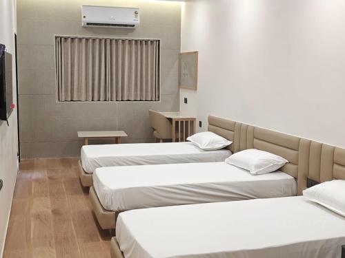 a room with three beds and a television in it at Hotel Krishiv- Sanand in Sānand