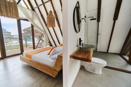 a bedroom with a bed and a bathroom with a toilet at El Embrujo Tintipan in Tintipan Island