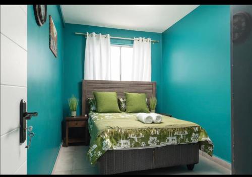 a bedroom with blue walls and a bed with green pillows at 94 Camarque Umdloti in Umdloti