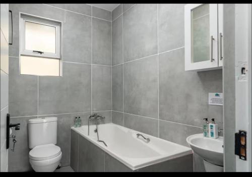a bathroom with a tub and a toilet and a sink at 94 Camarque Umdloti in Umdloti