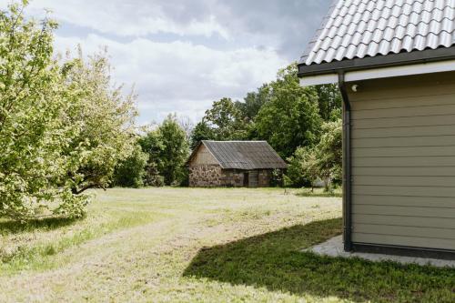 an old barn in a field next to a house at Obsenieki - moderna lauku sēta in Stalidzāni