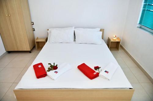 a white bed with two red pillows on it at Jasmine Apartments in Velipojë