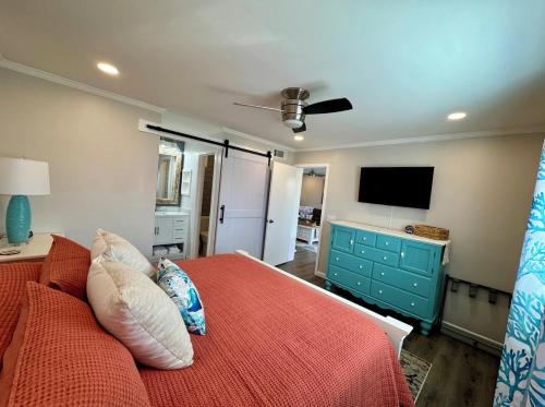a bedroom with a bed and a flat screen tv at Caribbean LYMM Cottage in Carolina Beach