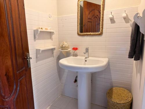 a white bathroom with a sink and a mirror at Bahari Paje Beach House in Paje
