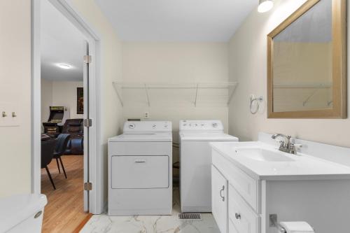 a white bathroom with two washers and a sink at The Brick House Georgetown in Georgetown
