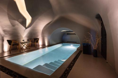 a swimming pool in a house with an archway at Kivotos Santorini - Preferred Hotels & Resorts in Imerovigli
