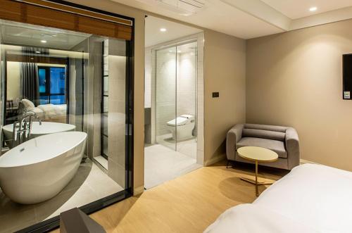 a bathroom with a tub and a bed and a sink at Brown Dot Hotel Ulsan Samsan in Ulsan